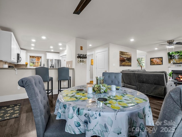 178 Flynn Ct, Lake Lure, NC 28746 - dining room featuring a warm lit fireplace, dark wood finished floors, ceiling fan, and a wealth of natural light
