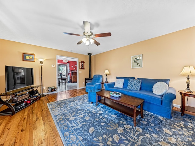 living room featuring hardwood / wood-style floors, ceiling fan, and a wood stove