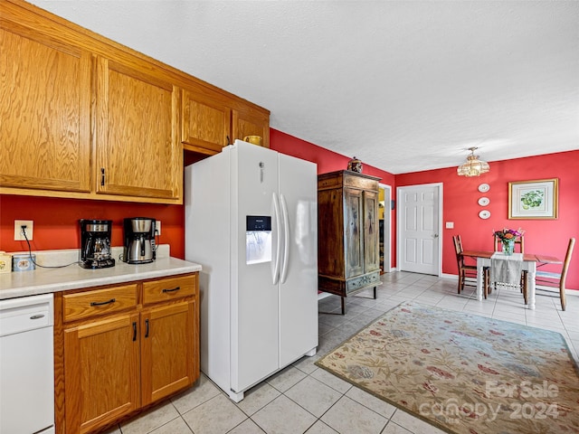 kitchen with a textured ceiling, light tile patterned floors, a chandelier, and white appliances