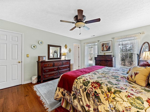 bedroom with ceiling fan, dark hardwood / wood-style flooring, and a textured ceiling