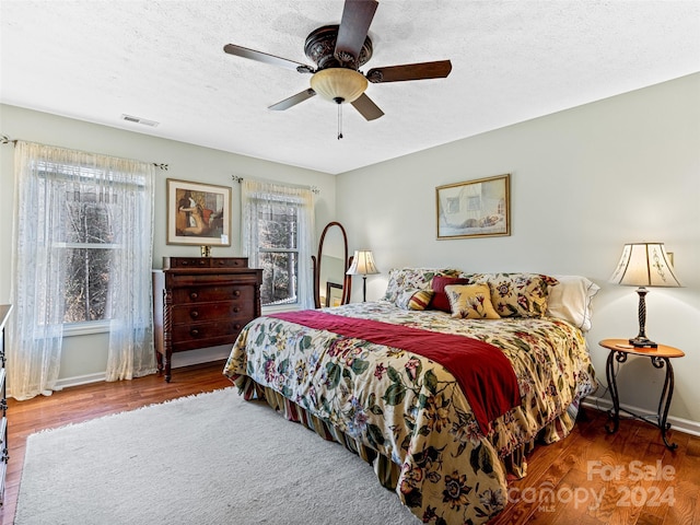 bedroom featuring ceiling fan, wood-type flooring, and a textured ceiling