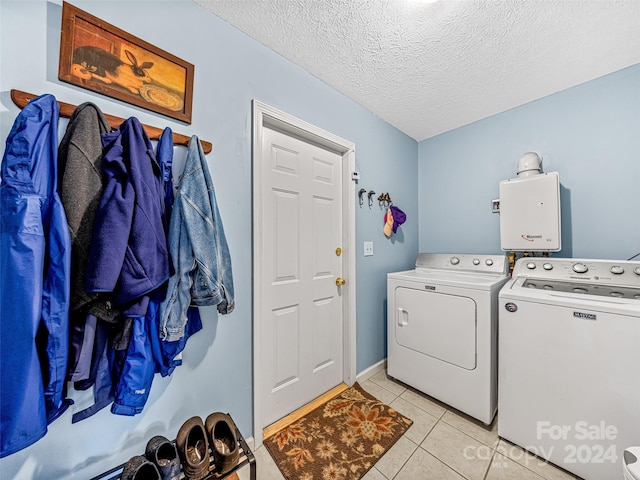 laundry area featuring washing machine and dryer, light tile patterned flooring, and a textured ceiling