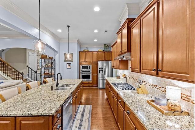 kitchen featuring appliances with stainless steel finishes, dark hardwood / wood-style flooring, sink, hanging light fixtures, and an island with sink