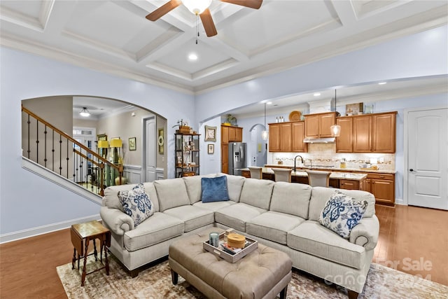 living room featuring coffered ceiling, dark hardwood / wood-style floors, ceiling fan, ornamental molding, and beamed ceiling