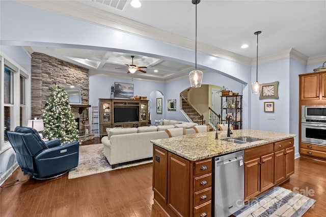 kitchen with sink, light stone counters, pendant lighting, a center island with sink, and appliances with stainless steel finishes