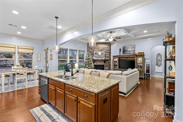 kitchen featuring light stone countertops, dark hardwood / wood-style flooring, a kitchen island with sink, sink, and decorative light fixtures