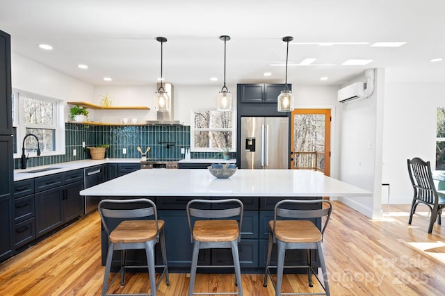 kitchen featuring decorative backsplash, a kitchen bar, sink, stainless steel fridge with ice dispenser, and a kitchen island