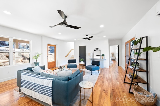 living room with ceiling fan, a wall mounted AC, and light hardwood / wood-style flooring