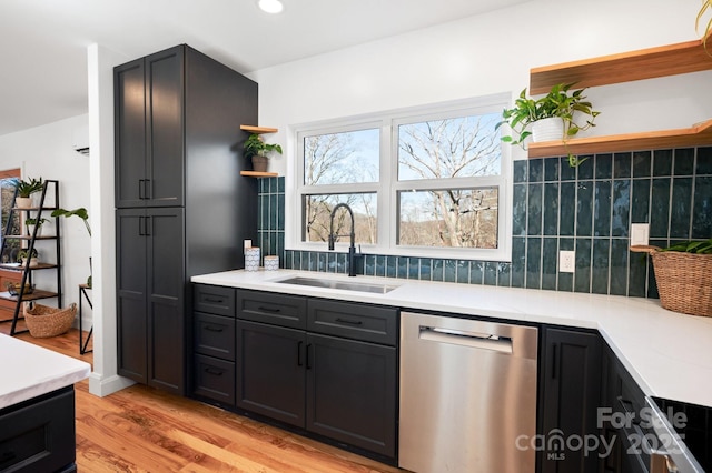 kitchen with stainless steel dishwasher, decorative backsplash, light hardwood / wood-style floors, and sink