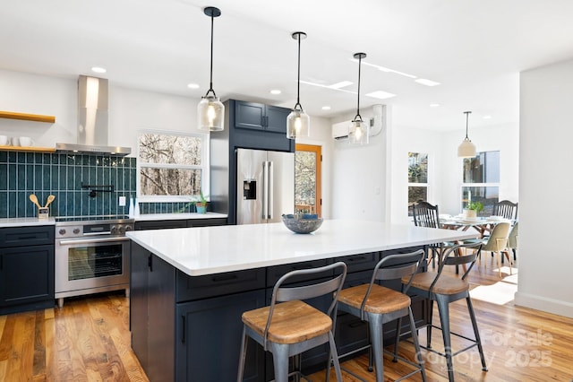 kitchen with decorative backsplash, light wood-type flooring, premium appliances, extractor fan, and a kitchen island