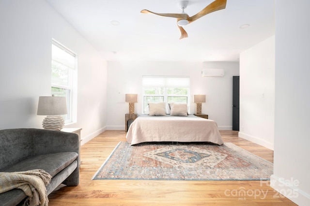 bedroom with a wall mounted air conditioner, ceiling fan, and light hardwood / wood-style floors