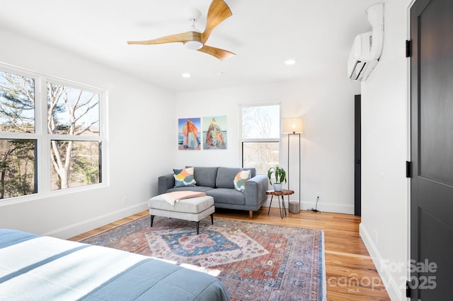 bedroom with a wall mounted AC, light wood-type flooring, and ceiling fan