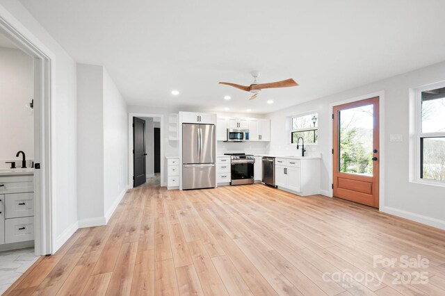 kitchen featuring ceiling fan, sink, white cabinets, and stainless steel appliances