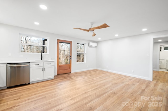 unfurnished living room featuring light hardwood / wood-style floors, a wall unit AC, ceiling fan, and sink