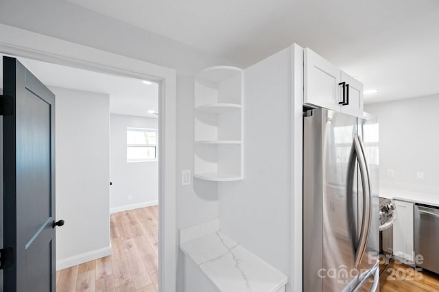 kitchen featuring white cabinetry, light stone counters, light wood-type flooring, and stainless steel appliances