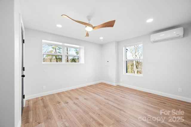 empty room featuring light wood-type flooring, an AC wall unit, ceiling fan, and a healthy amount of sunlight