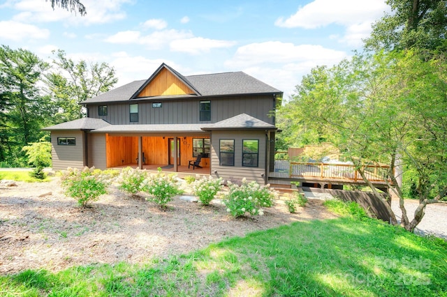 rear view of house featuring a lawn and a deck