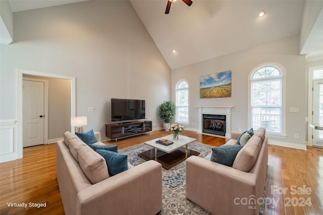 living room with ceiling fan, high vaulted ceiling, and light wood-type flooring