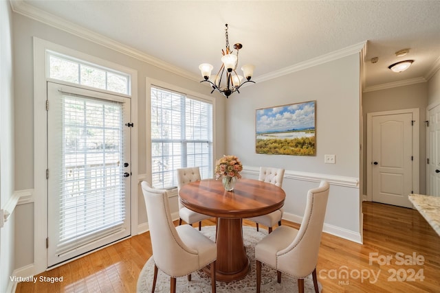 dining room with light hardwood / wood-style floors, crown molding, and a chandelier