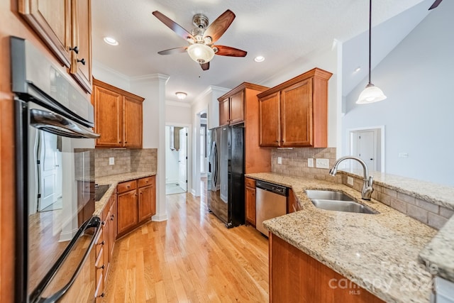 kitchen with sink, hanging light fixtures, light hardwood / wood-style flooring, light stone countertops, and appliances with stainless steel finishes