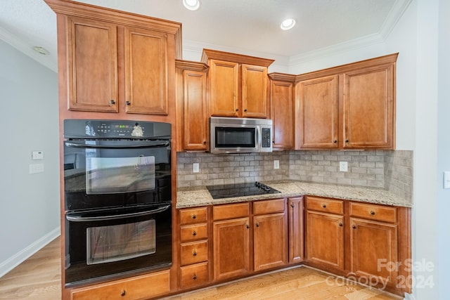 kitchen with backsplash, black appliances, light hardwood / wood-style flooring, light stone countertops, and ornamental molding