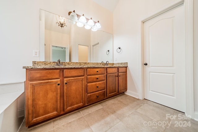 bathroom with tile patterned flooring, vanity, and an inviting chandelier