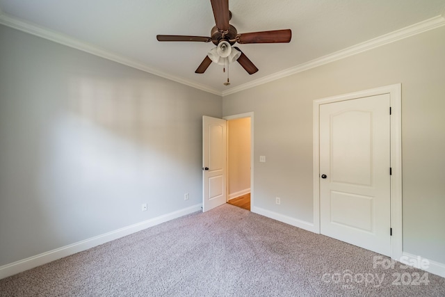 carpeted spare room with ceiling fan and crown molding