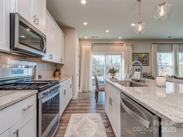 kitchen with white cabinetry, sink, stainless steel appliances, pendant lighting, and decorative backsplash