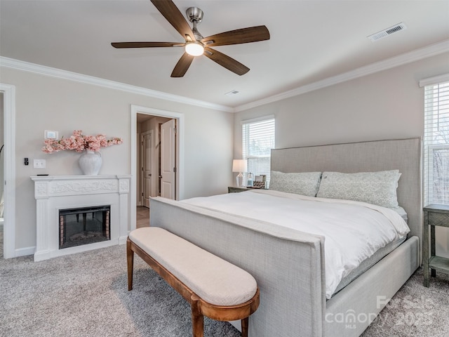 carpeted bedroom with multiple windows, ceiling fan, and ornamental molding