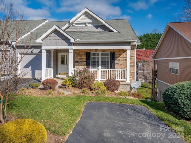 view of front of house featuring a front lawn, covered porch, and a garage