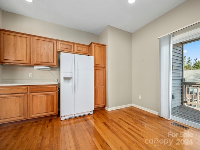 kitchen featuring light wood-type flooring, white fridge with ice dispenser, and a wealth of natural light