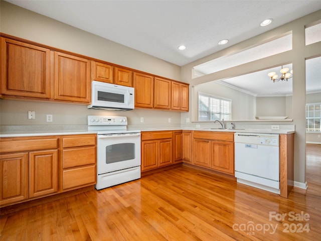 kitchen featuring hanging light fixtures, light hardwood / wood-style flooring, a notable chandelier, white appliances, and ornamental molding