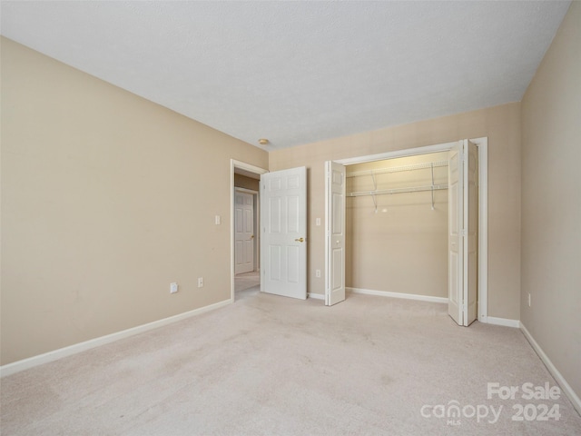 unfurnished bedroom featuring light carpet and a closet