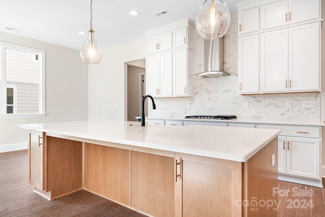 kitchen featuring white cabinets, stainless steel gas stovetop, a spacious island, and hardwood / wood-style flooring