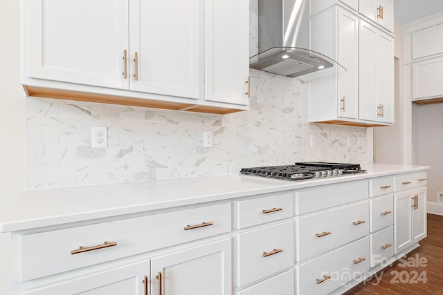 kitchen featuring wall chimney exhaust hood, dark hardwood / wood-style flooring, white cabinetry, and backsplash