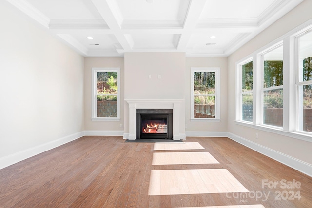 unfurnished living room featuring beamed ceiling, a healthy amount of sunlight, and light wood-type flooring