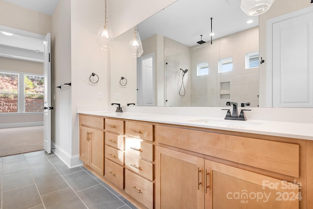 bathroom featuring tile patterned flooring, vanity, and tiled shower