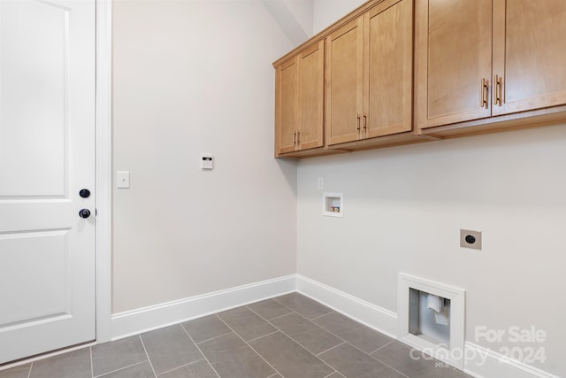 washroom featuring electric dryer hookup, cabinets, dark tile patterned flooring, and washer hookup