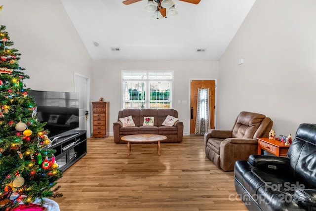 living room with ceiling fan, high vaulted ceiling, and light hardwood / wood-style flooring