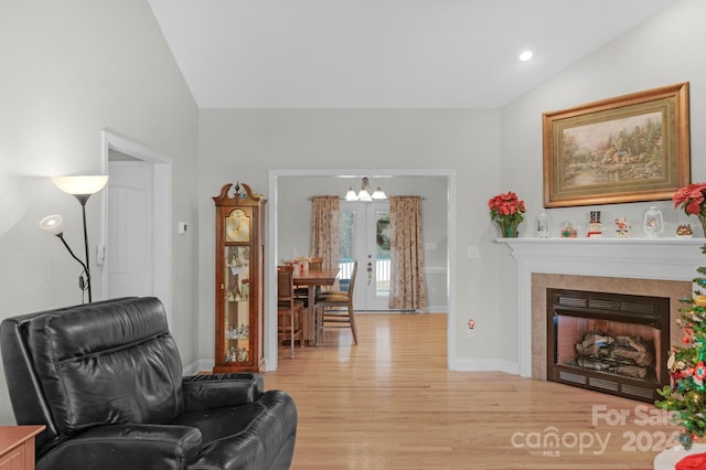 sitting room featuring a fireplace, french doors, light wood-type flooring, and lofted ceiling