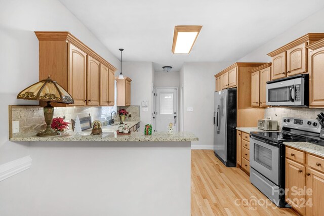 kitchen with stainless steel appliances, light stone counters, light hardwood / wood-style flooring, kitchen peninsula, and decorative backsplash