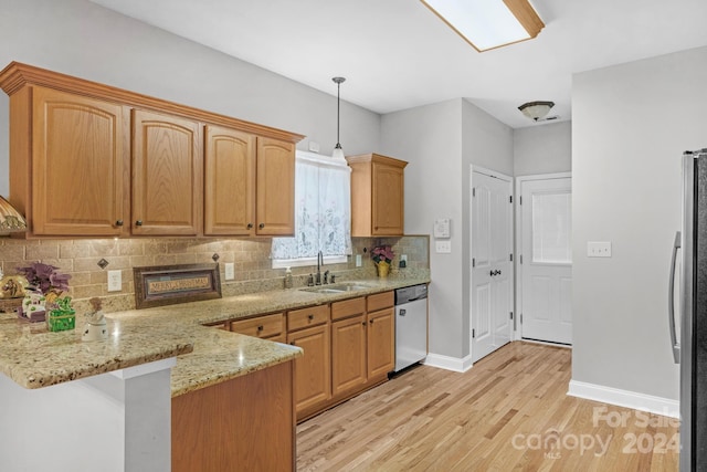 kitchen with light stone countertops, sink, pendant lighting, appliances with stainless steel finishes, and light wood-type flooring