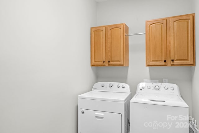 washroom with washing machine and clothes dryer and cabinets