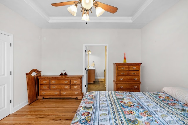 bedroom featuring a tray ceiling, light hardwood / wood-style flooring, ceiling fan, and crown molding