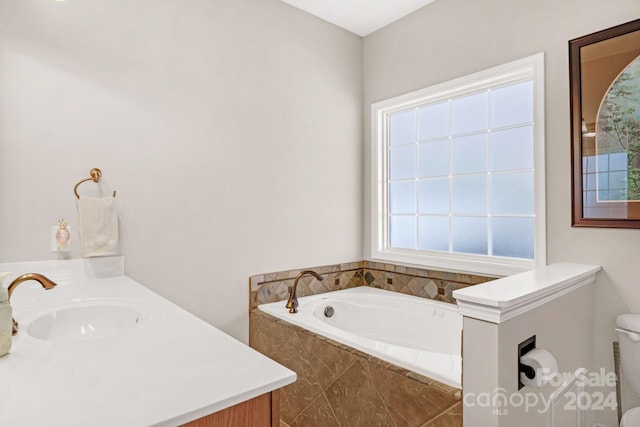 bathroom featuring tiled tub and vanity