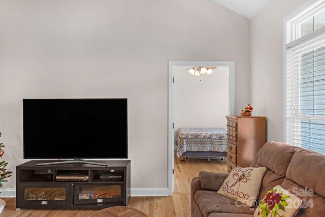 living room featuring an inviting chandelier, light wood-type flooring, and vaulted ceiling