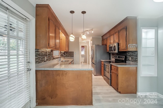 kitchen with sink, appliances with stainless steel finishes, tasteful backsplash, decorative light fixtures, and light hardwood / wood-style floors