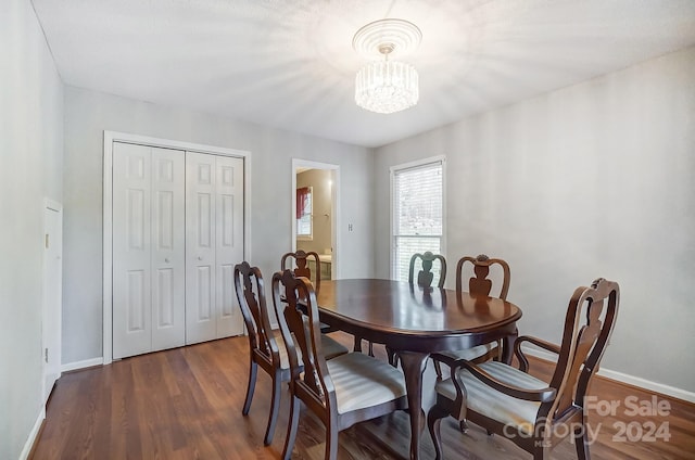 dining area with dark hardwood / wood-style floors and an inviting chandelier