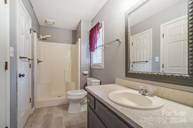 bathroom with vanity, hardwood / wood-style flooring, toilet, and walk in shower