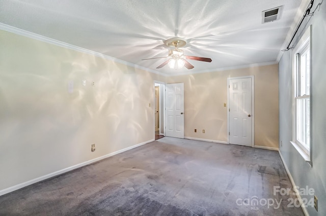 carpeted empty room featuring ceiling fan, crown molding, and a wealth of natural light